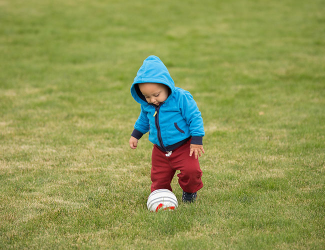 young kid kicking a ball.