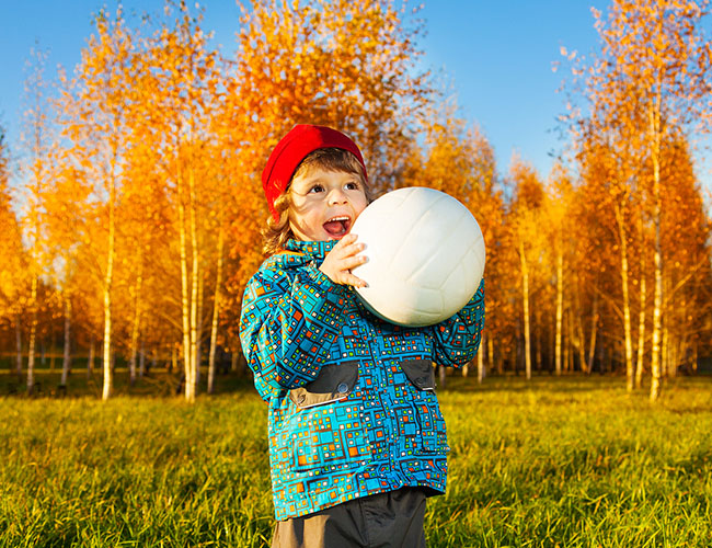 4 year old boy catches a volleyball.