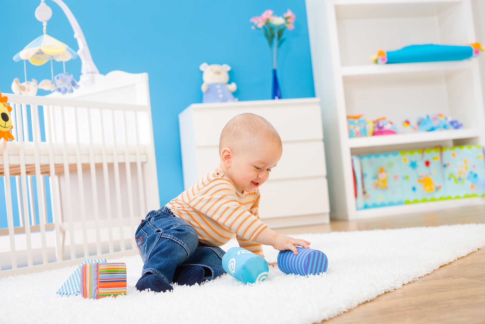 8 month old sitting upright playing with toys.