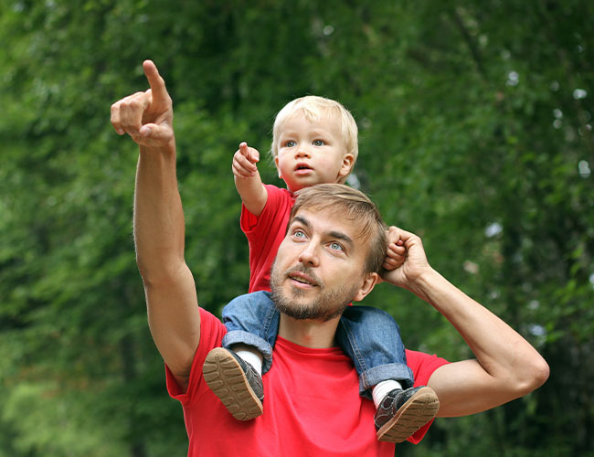13-18 month old kid on father's shoulders pointing.