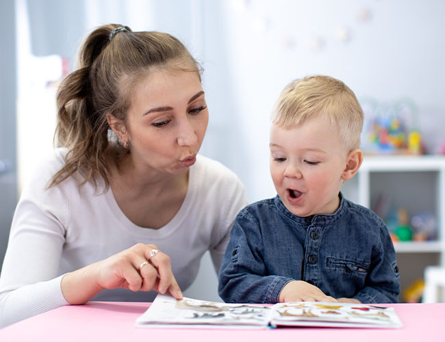 2 - 3 year old reading a book with a teacher.